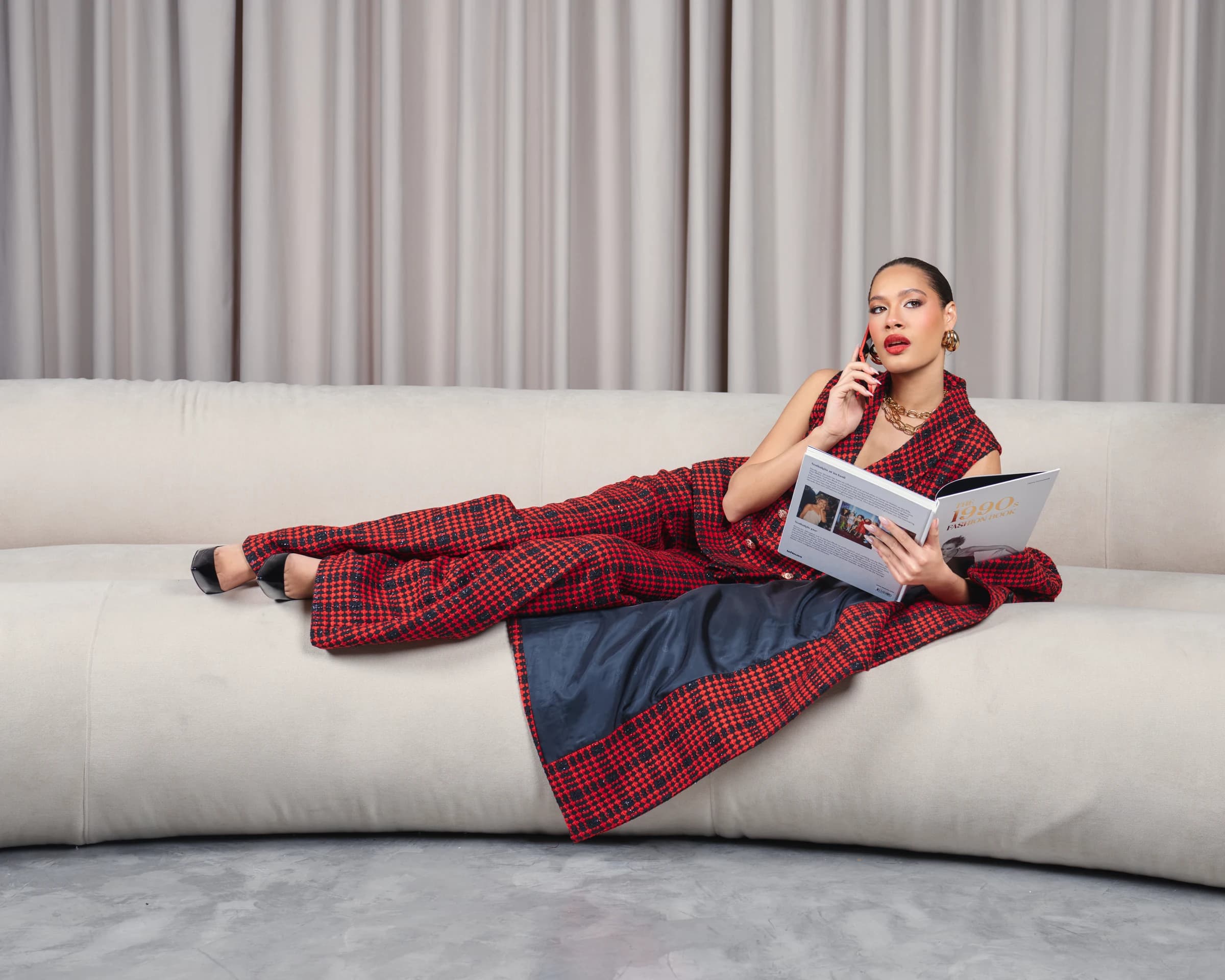 Editorial portrait by Deine Photography, red checked suit on a pale sofa with a fashion book